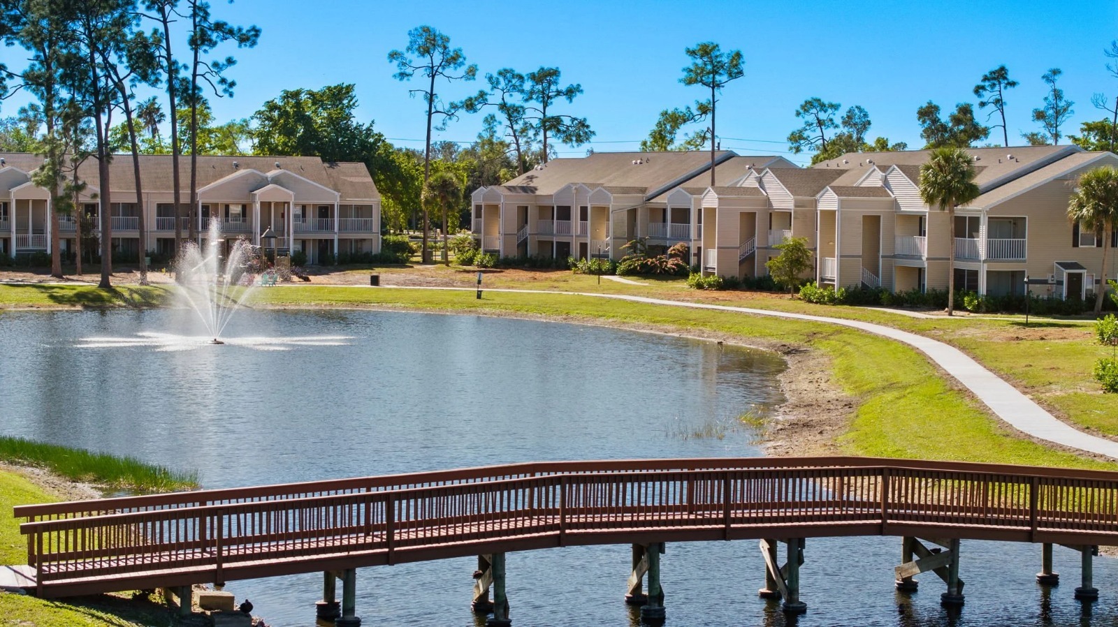 Sunny multifamily apartment community with pond and landscaping